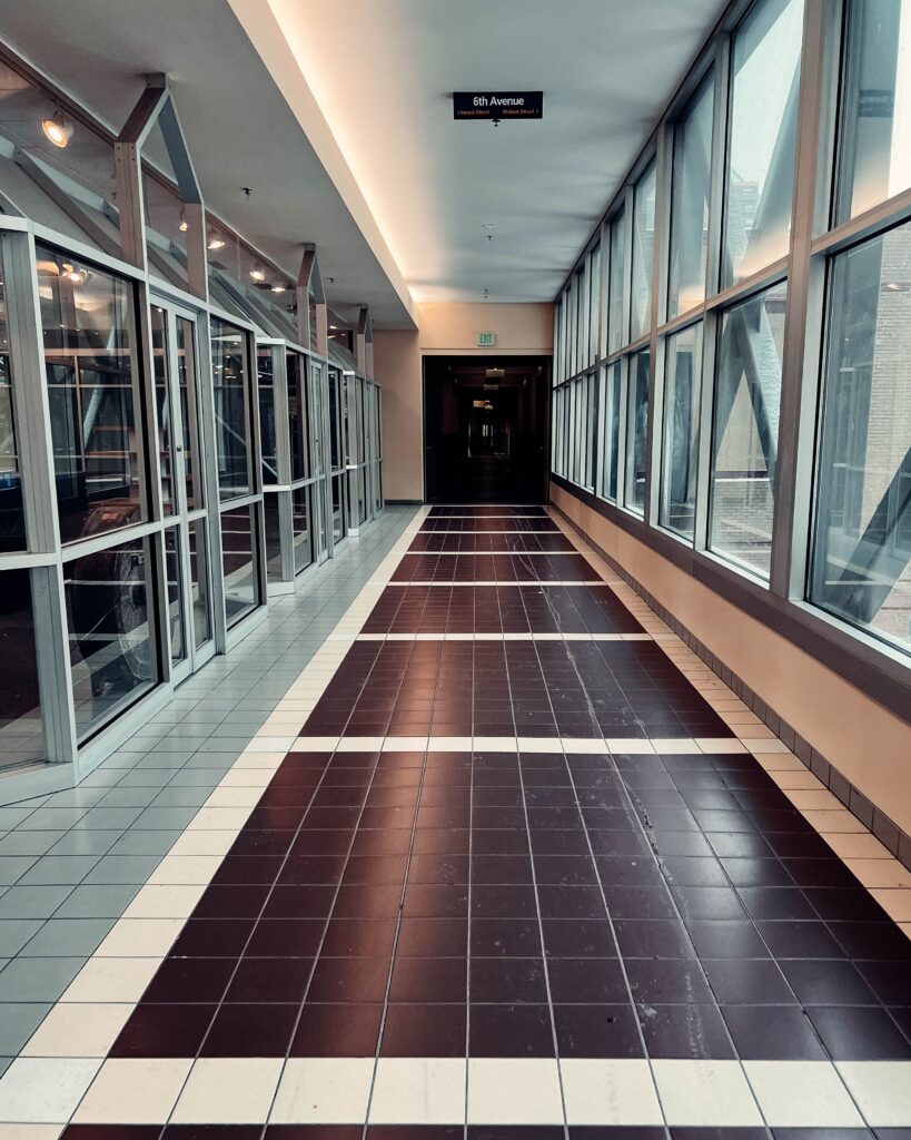 A modern corridor with glass walls and tiled flooring in an urban building.