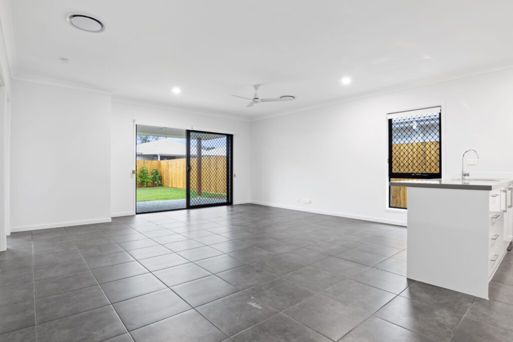 Bright and empty modern living room with sliding doors and tiled floor.
