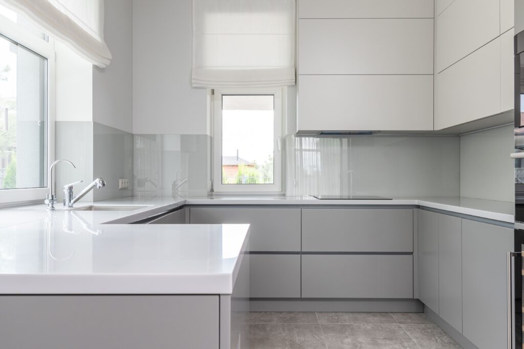 Modern interior of contemporary kitchen with white clean new furniture and small windows in daytime