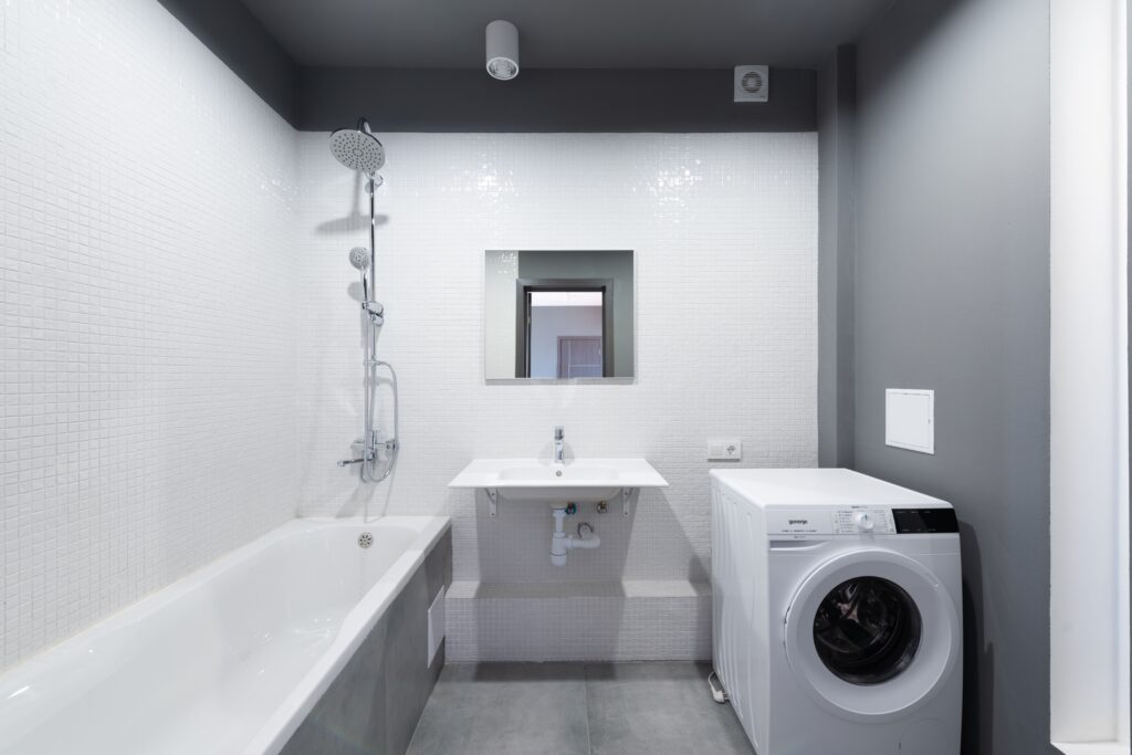 Modern bathroom design featuring bathtub, sink, and washing machine.